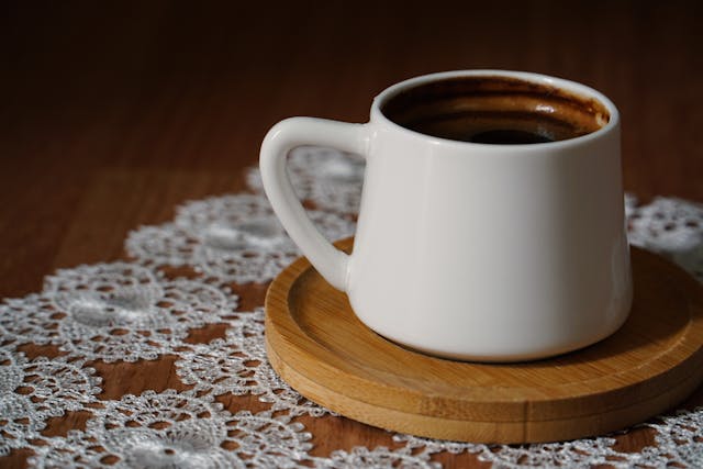 A traditional white Turkish coffee cup (fincan) overturned on its saucer, with coffee grounds starting to set for a fortune-telling session