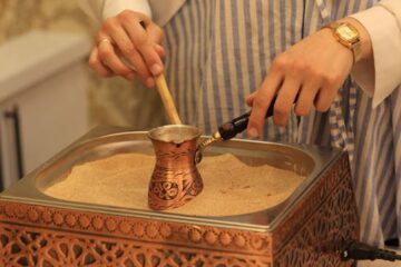 A traditional copper cezve, a Turkish coffee cup, and a bag of finely ground coffee beans