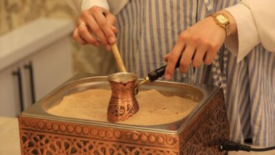A traditional copper cezve, a Turkish coffee cup, and a bag of finely ground coffee beans